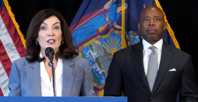 New York Governor Kathy Hochul delivers remarks from a podium and New York City Mayor Eric Adams looks on.