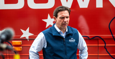 Ron DeSantis looks down in a dress shirt and sweater vest