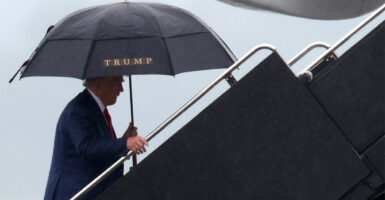 President Donald Trump boards his plane, umbrella in hand