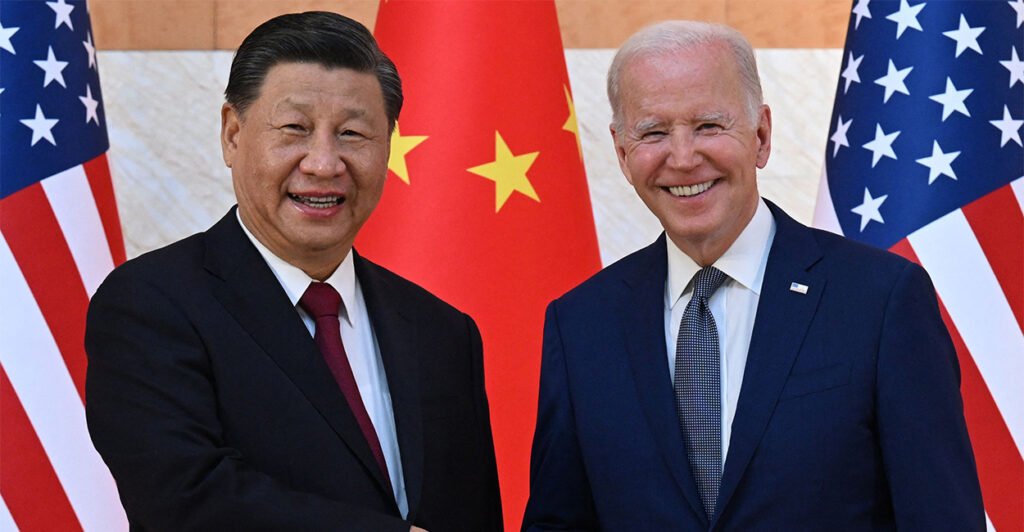 A smiling President Joe Biden and China's President Xi Jinping shake hands