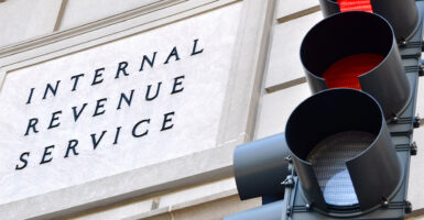 Internal Revenue Service sign on IRS building with a traffic signal in the foreground indicating a red light.