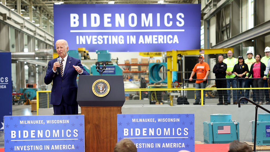President Joe Biden speaks in front of a sign reading "Bidenomics."