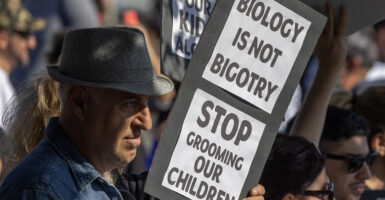 A man holds a sign reading "biology is not bigotry"