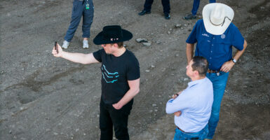 Elon Musk stand near the Mexico border in Eagle Pass, Texas filming videos on his phone.