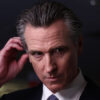 Gavin Newsom in a suit looks skeptical in a suit.