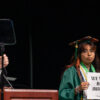 George Mason University graduate holds a sign reading "We will not debate humanity" while Gov. Glenn Youngkin speaks.