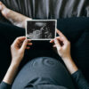 pregnant woman looking at ultrasound photo of her baby