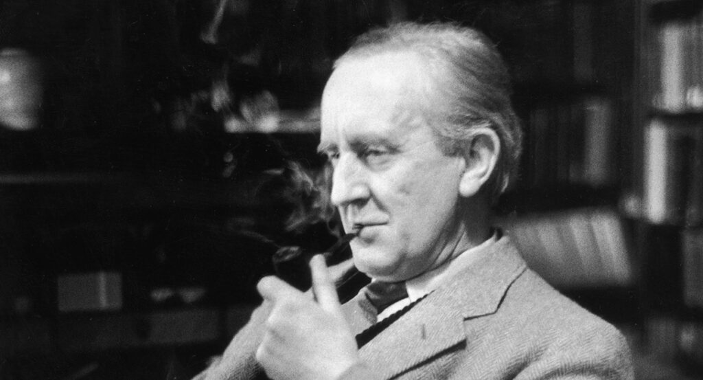 JRR Tolkien smokes a pipe in a suit as he sits in front of a bookcase