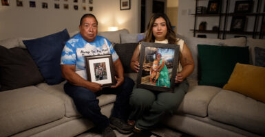 Emilio and Elisa Tambunga sit on their couch holding family photos.