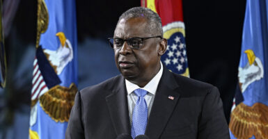 Secretary of Defense Lloyd Austin wearing a black suit and a black tie with an American flag pin.