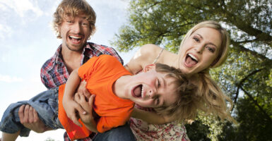 Laughing father, mother, and young son playing outdoors
