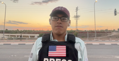 Reporter Julio Rosas outside with a baseball cap and a bulletproof vest with a U.S. flag and the word press across the chest