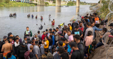 A large group of illegal aliens stand on the bank of the Rio Grande after crossing the border from Mexico.