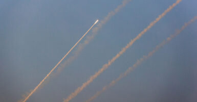 Rockets fly towards Israel against a blue sky.