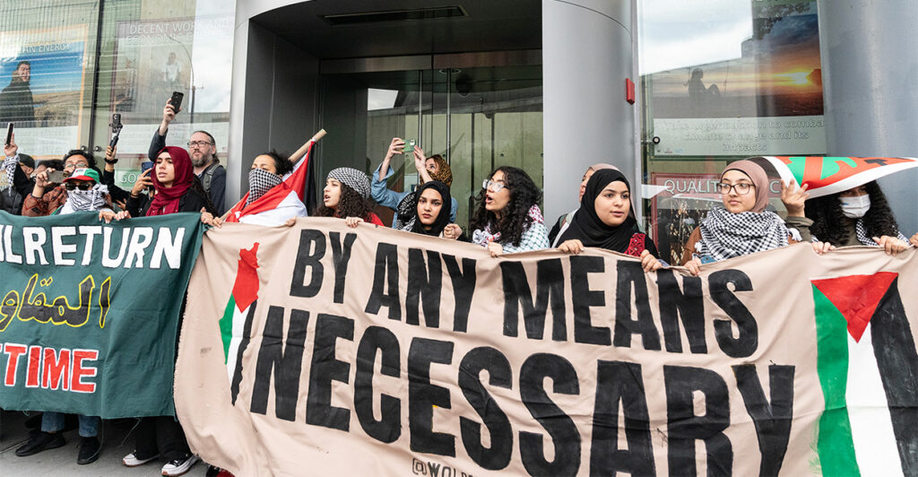 Pro-Palestinian supporters holding a sign saying, "By any means necessary"