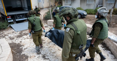 Four Israel Defense Force soldiers carry a body bag of a civilian killed in the attacks by Hamas.