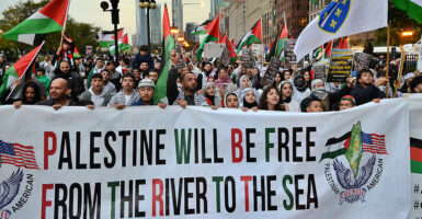 Pro-Palestine protesters march behind a banner reading 