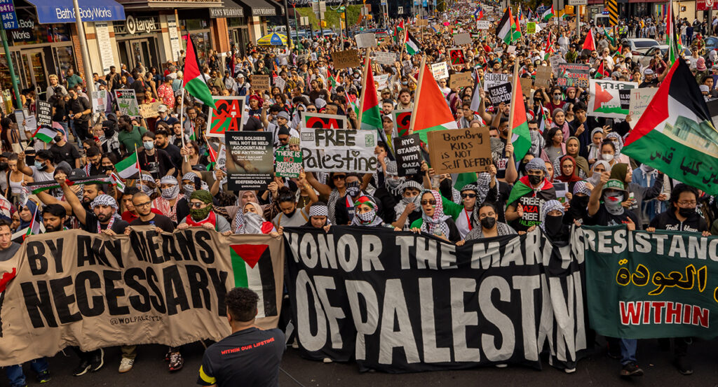 Protesters in New York City march with banners reading "By any means necessary," and "Free Palestine."
