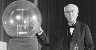 Thomas Edison puts his hand on a lightbulb