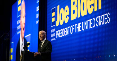 Joe Biden stands on stage in a suit and gives a speech.
