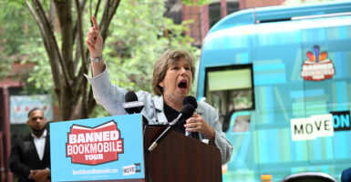 Randi Weingarten stands behind a podium with a sign that says "Banned Bookmobile" and yells into a microphone with her right hand raised