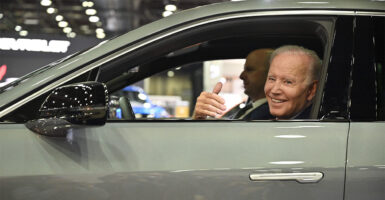 Joe Biden sitting at the wheel of an electric car at an auto show