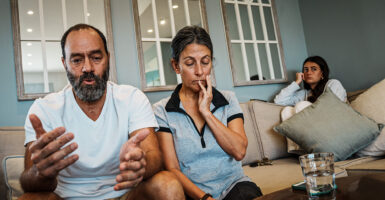 a dad, mom and daughter sit together on a couch in distress