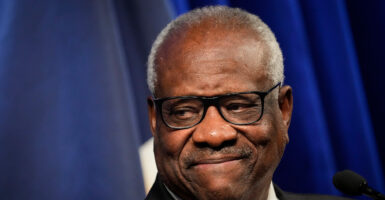 Clarence Thomas smiles in a black suit