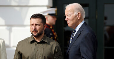 Volodymyr Zelenskyy wears green cargo outfit, stands next to Joe Biden who wears a dark blue suit.