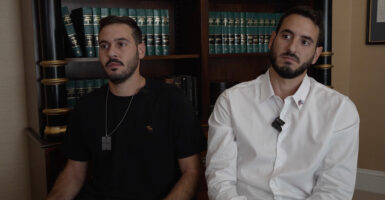 Brothers Ido (left) and Yonatan Lulu-Shamriz sit in front of a bookshelf for an interview with The Daily Signal.