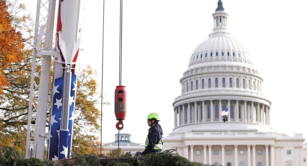 A construction worker stands with a crane in front of the U.S. Capitol
