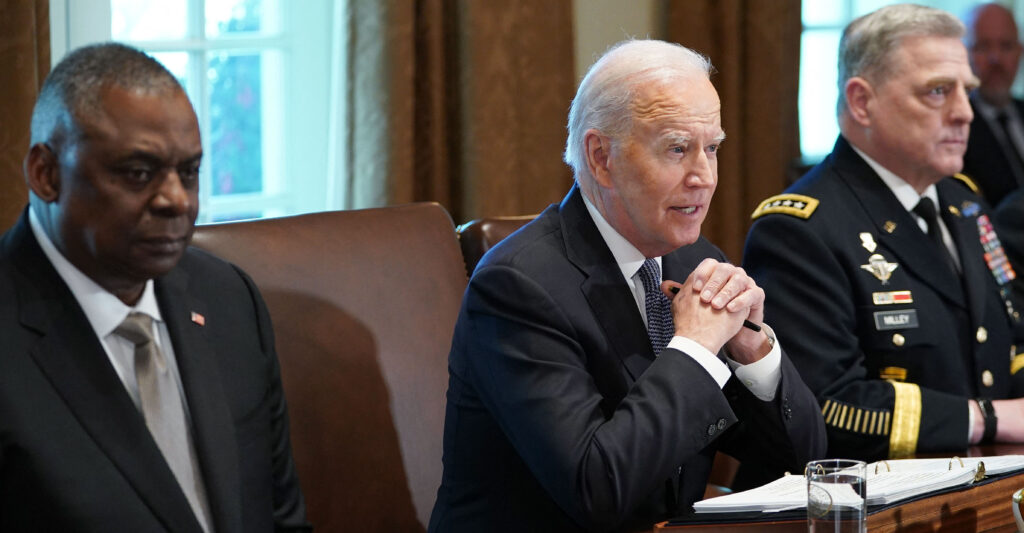 Lloyd Austin and Joe Biden in suits sit next to Mark Milley in a uniform.
