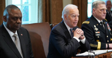 Lloyd Austin and Joe Biden in suits sit next to Mark Milley in a uniform.