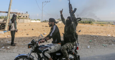 A Hamas terrorist celebrates on a motorcycle, holding a machine gun