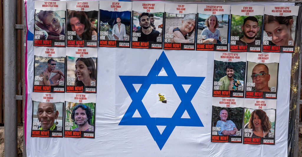 Photos of the hostages taken by Hamas hang on an Israeli flag.