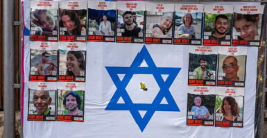 Photos of the hostages taken by Hamas hang on an Israeli flag.