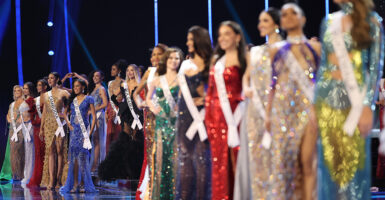miss universe contestants stand on stage in formal wear