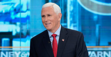Former Vice President Mike Pence smiles in a suit and red tie.