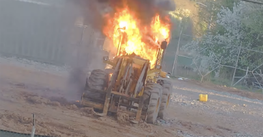 A tractor burns after rioters threw a Molotov cocktail at it.