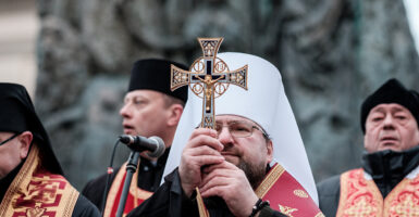 a Ukrainian priest holds a crucifix in front of his face
