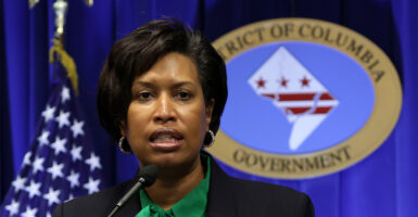 DC Mayor Muriel Browser In front of the microphone with flag and DC government logo behind her