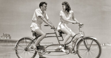 a man and a woman ride a bike on the beach
