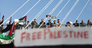 Protestors stand on a bridge behind a 'free palestine' banner