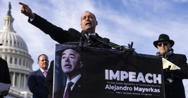 Rep. Bob Good speaks at a podium at a news conference with the U.S. Capitol in the background with a sign on the podium calling for the impeachment of Homeland Security Secretary Alejandro Mayorkas
