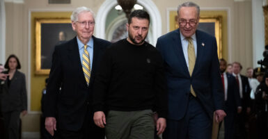 Mitch McConnell and Chuck Schumer in suits stand by Ukraine President Volodymyr Zelenskyy
