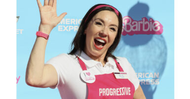 Flo from Progressive in pink in front of a Barbie logo