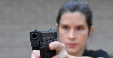 a woman pointing a pistol at the camera