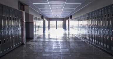 A long empty school hallway is seen lined with lockers.