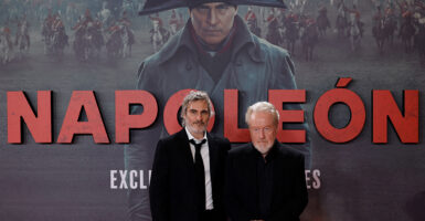 Joaquin Phoenix and Ridley Scott stand in front of a poster for the Napoleon 2023 movie
