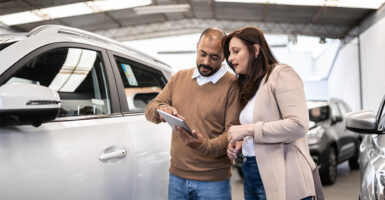 Salesman showing car to customer in a car dealership